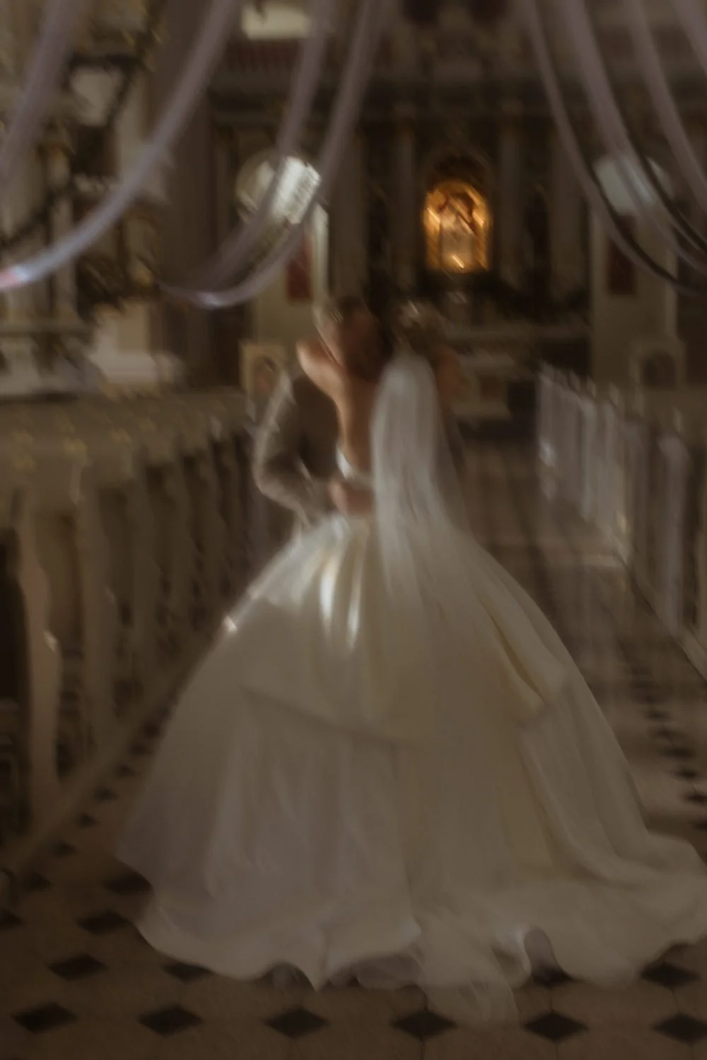 A bride in a white wedding gown standing on a staircase inside a church.