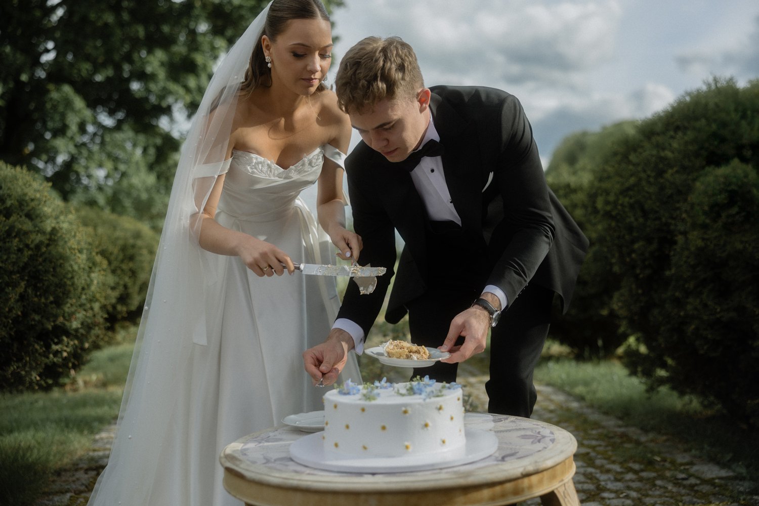 Bride and groom cutting wedding cake outdoors