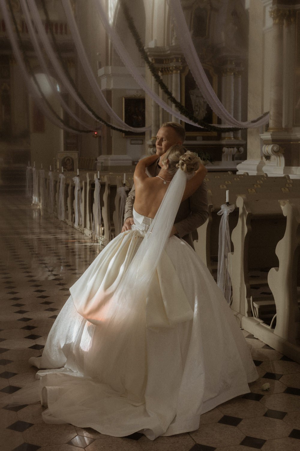 A bride and groom share a romantic dance inside a decorated church on their wedding day.
