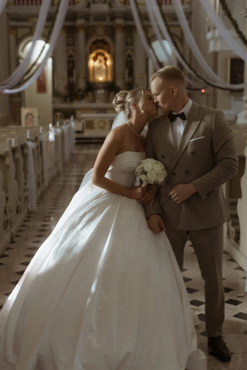 A bride and groom sharing a kiss inside a church during their wedding ceremony.