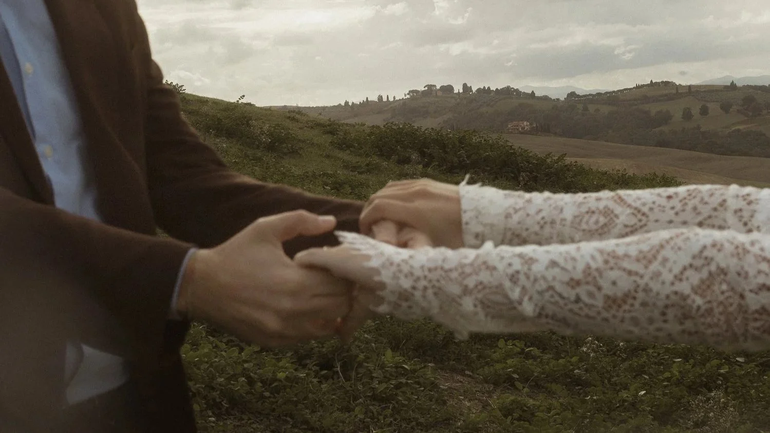 Bride and groom walking through Tuscany hills during golden hour