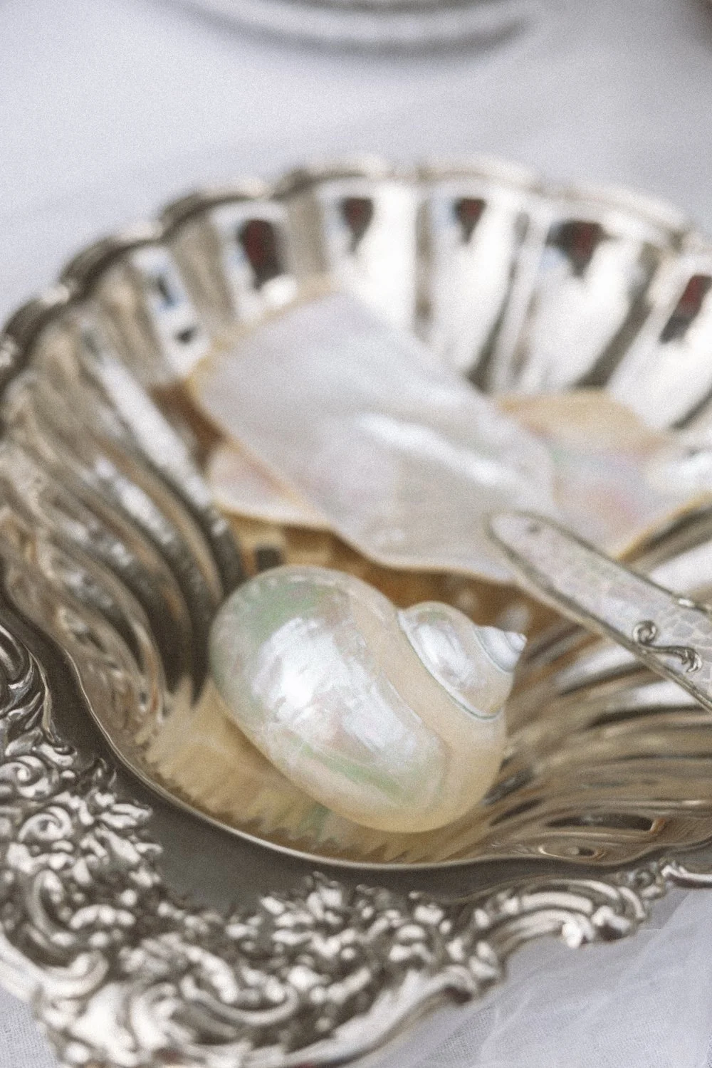 Pearl earrings, a jewelry box, and a pair of scissors on an ornate silver tray.