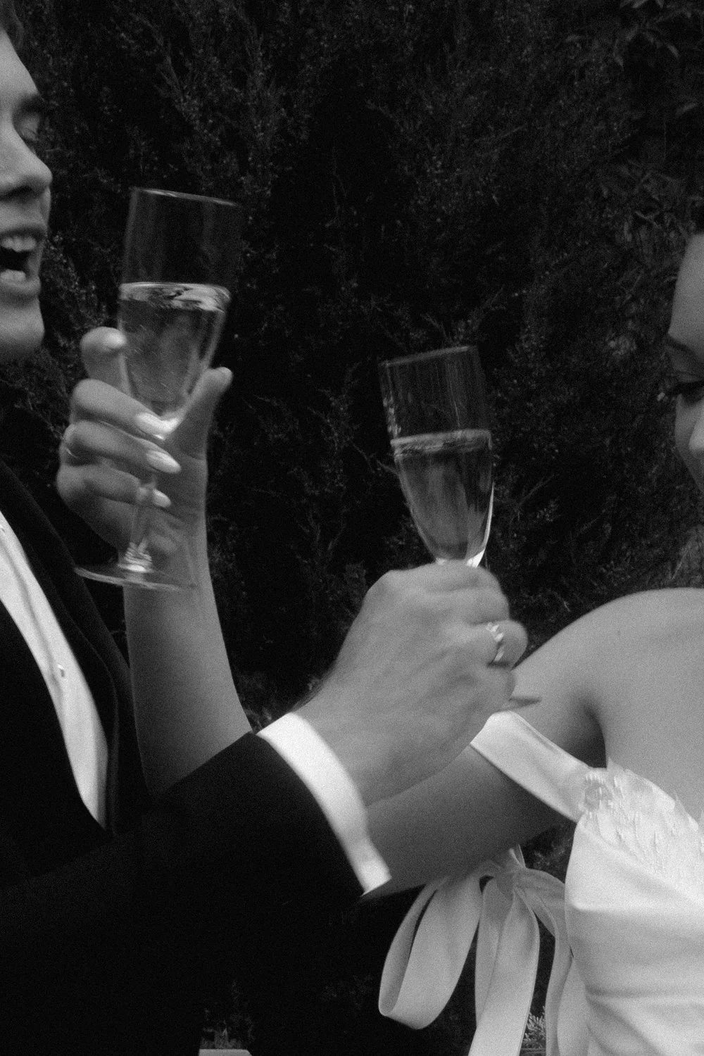 Two people in formal attire sharing a toast with champagne glasses outdoors at night.