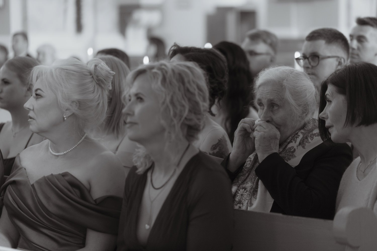 A diverse group of people sitting in pews, attentively listening during a formal event or service.