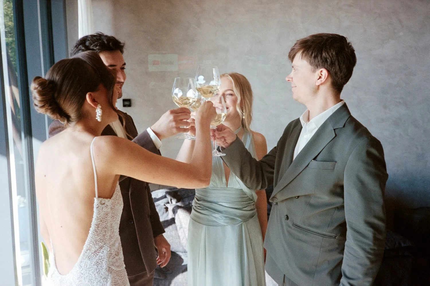 Group of people at a celebration raising glasses of white wine for a toast