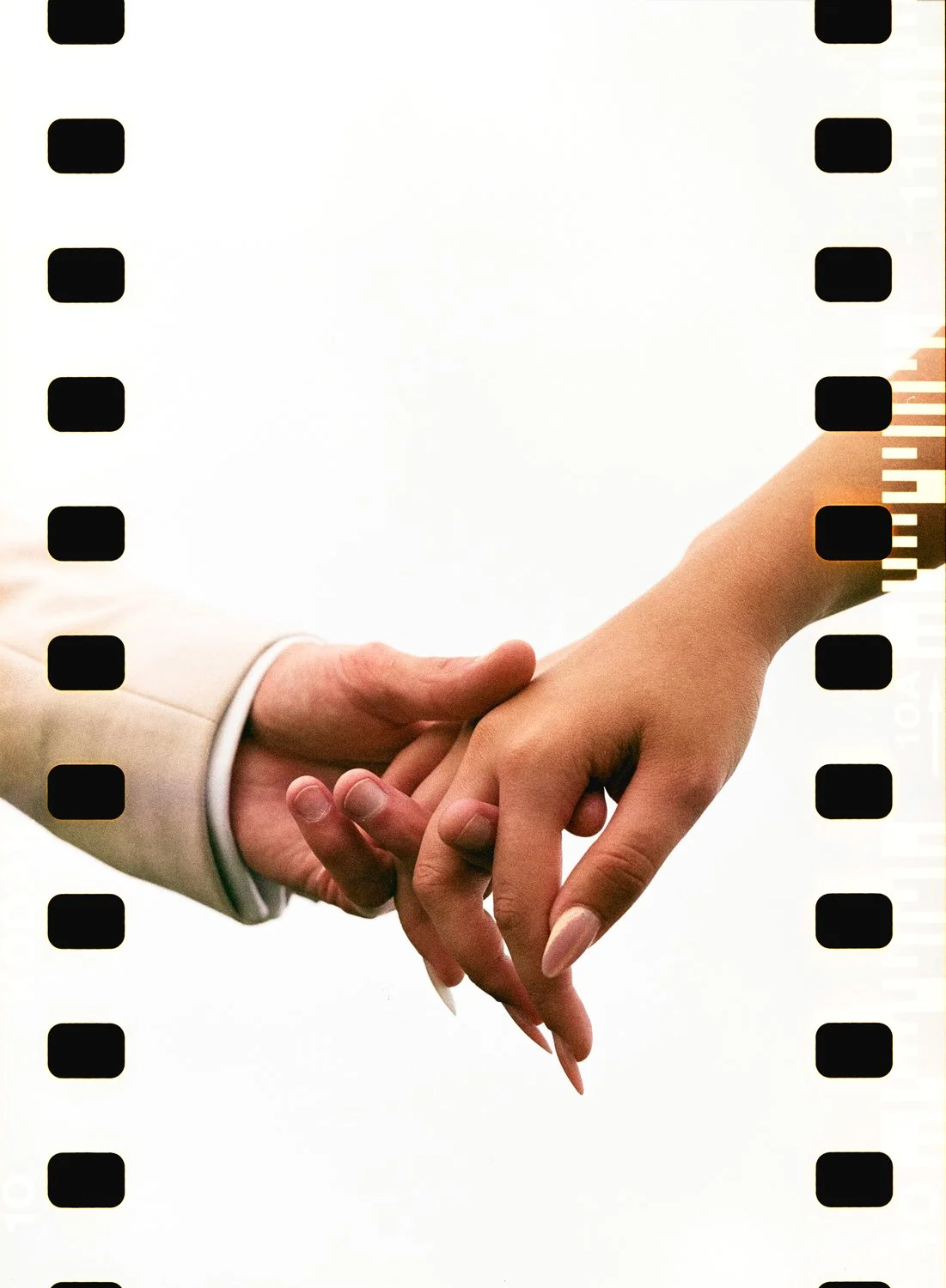 Two hands, one with a light-colored sleeve and the other with a bare arm, gently holding each other. The background is plain white.