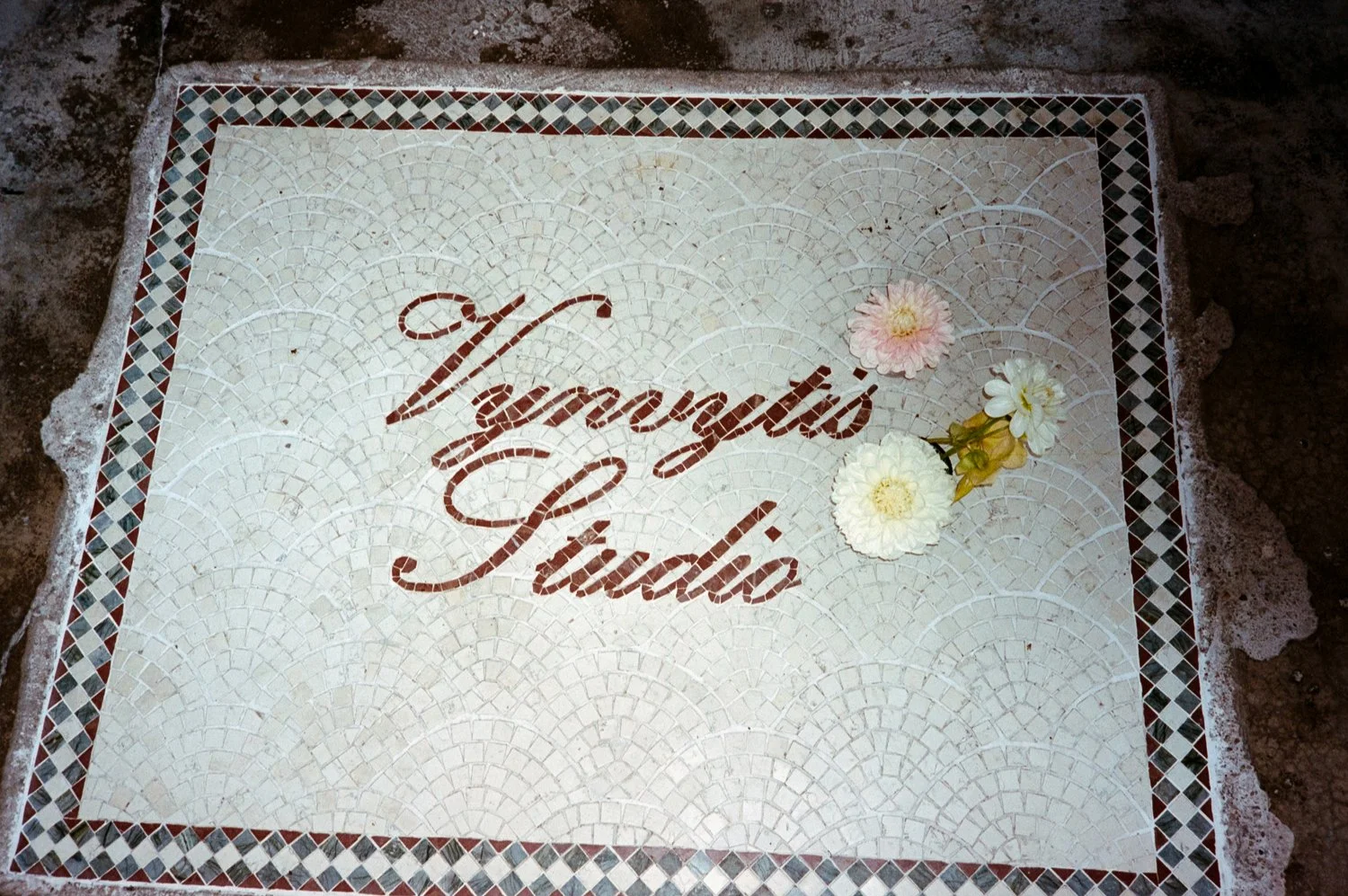 A mosaic tile floor with the words 'Vierge Marie' written in script and decorated with white and pink flowers.