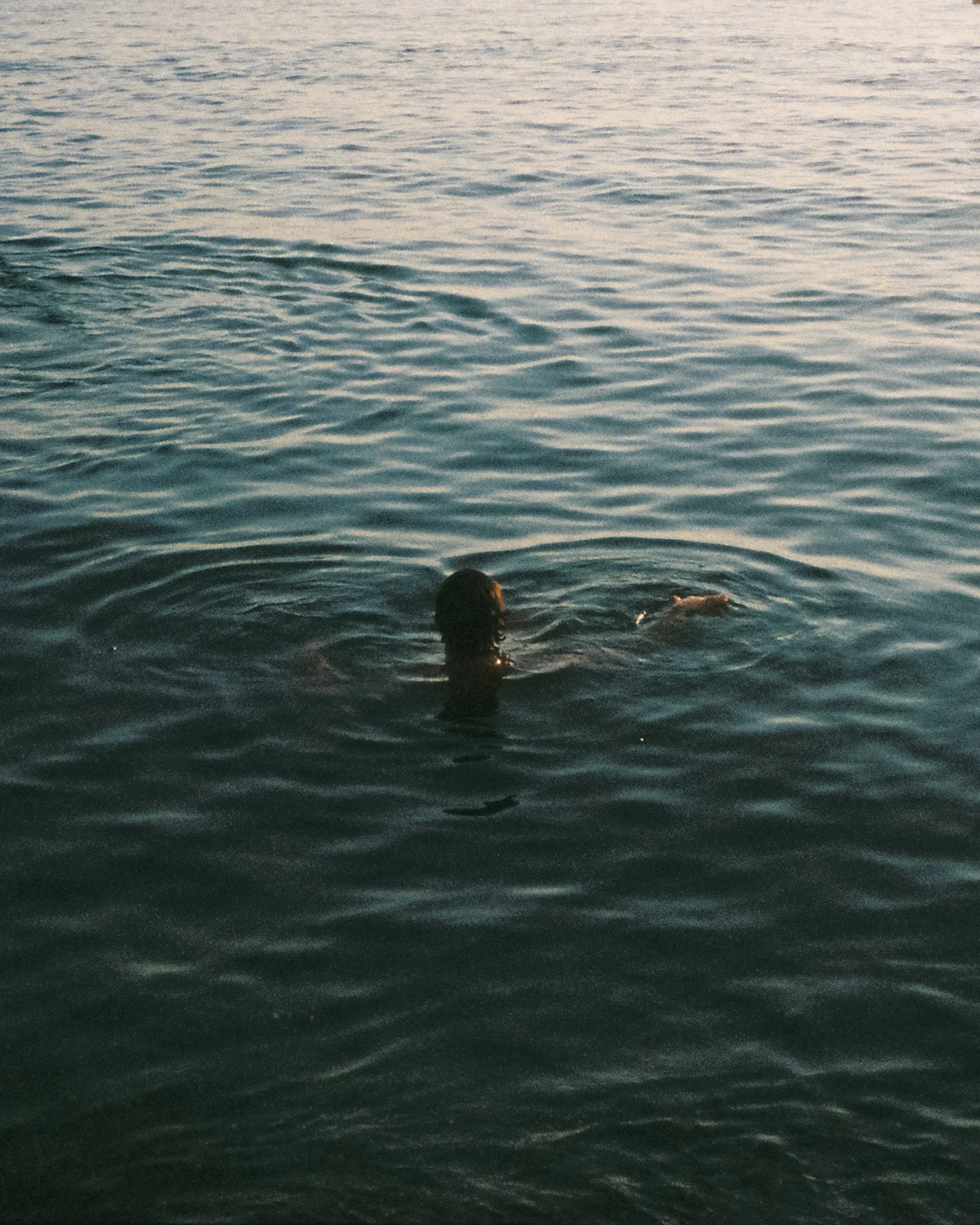 Young boy enjoying the sunset in the sea, Italy.