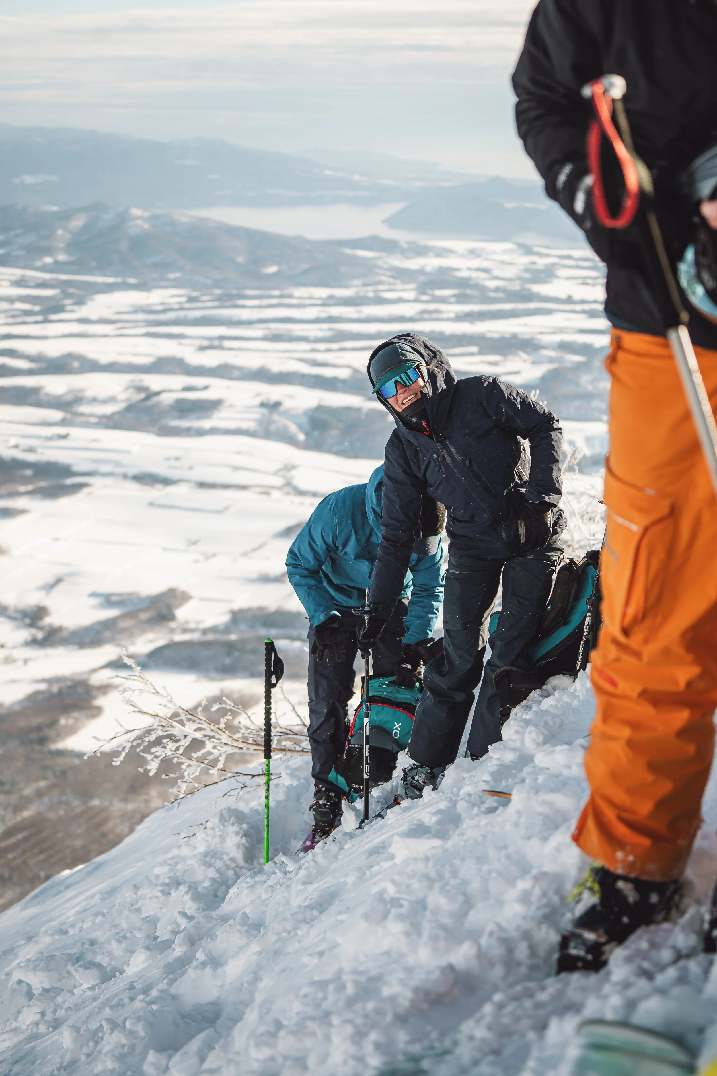 Group of people in winter gear climbing snowy mountain slope with a scenic landscape in the background
