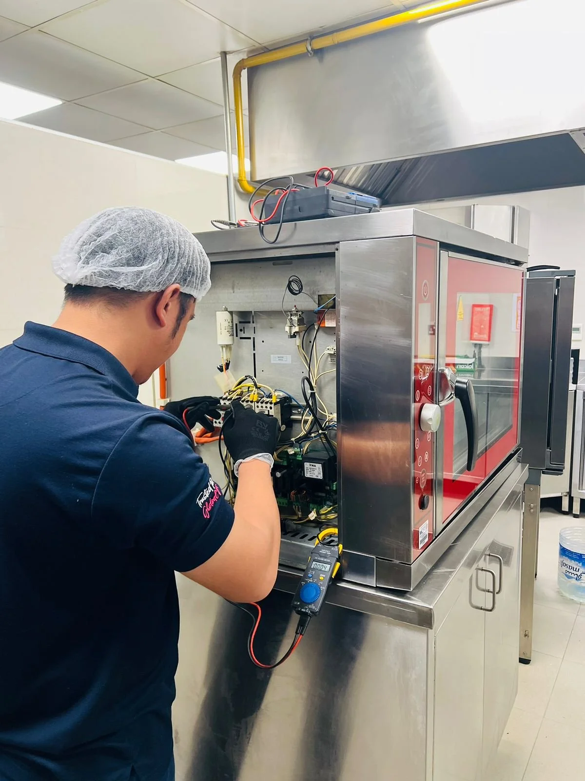 Technician working on the electronic components of a commercial oven or sterilizer in a professional kitchen or laboratory setting.