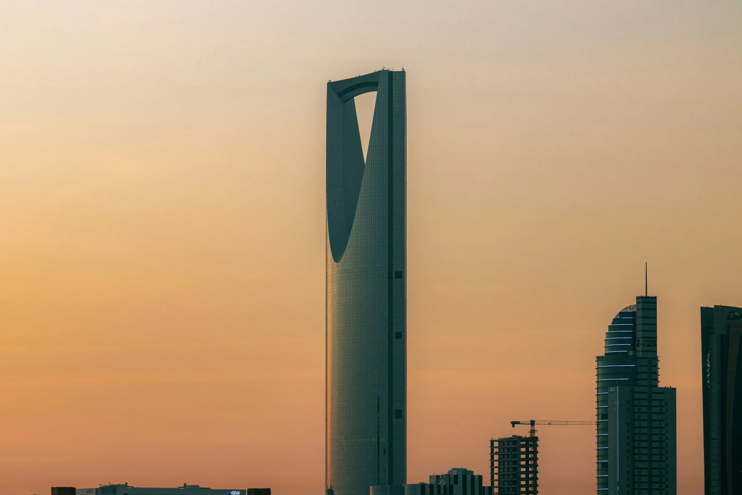 Skyline of Dubai during sunset with the Burj Al Arab hotel visible in the distance and several other skyscrapers under construction.