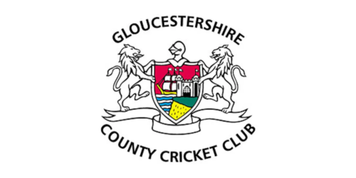 The logo of Gloucestershire County Cricket Club featuring a shield with a castle, lions, and a colorful section, flanked by two lions and the club's name.