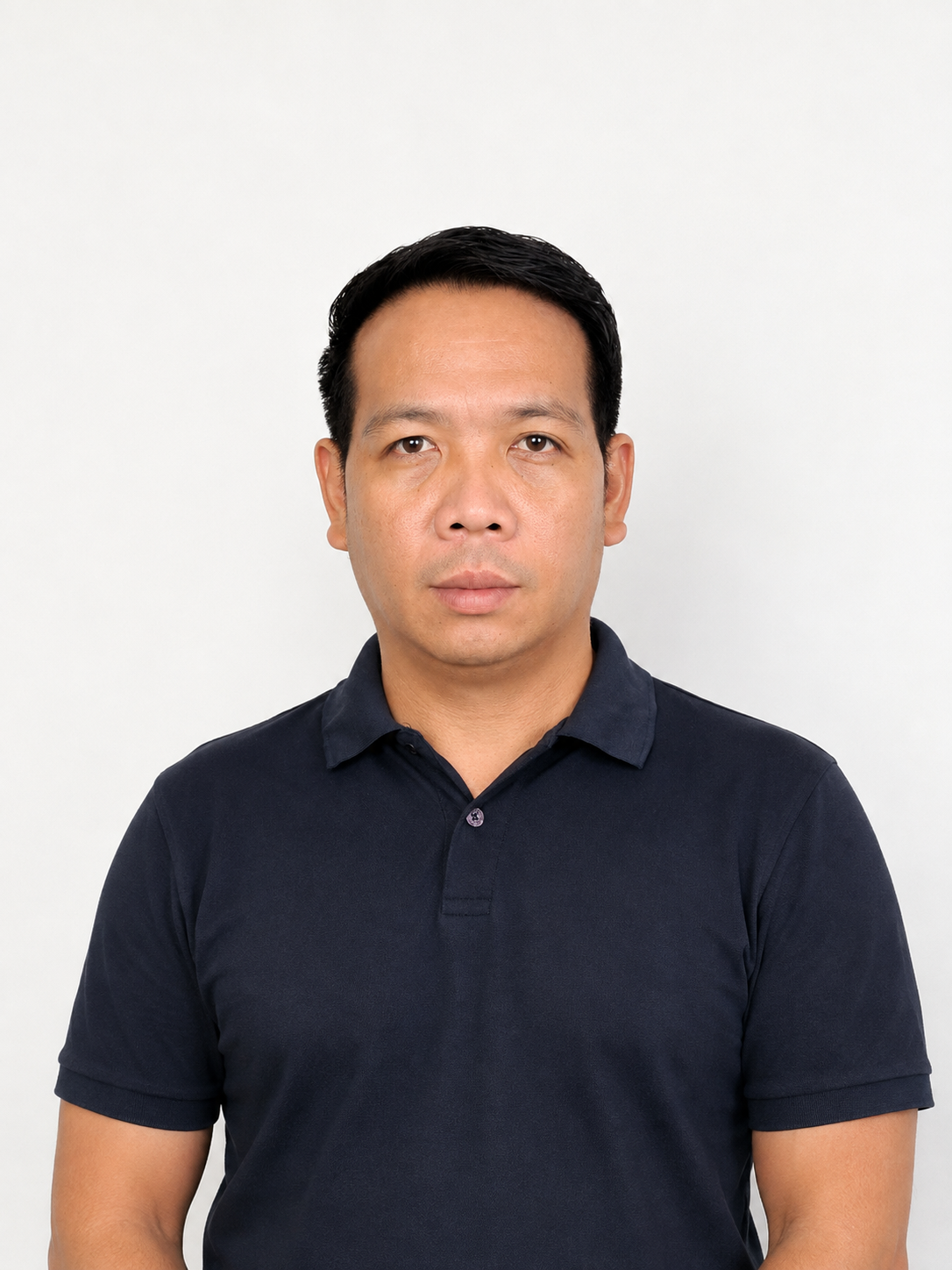 Portrait of a man with short black hair, wearing a navy blue polo shirt, standing against a plain white background.