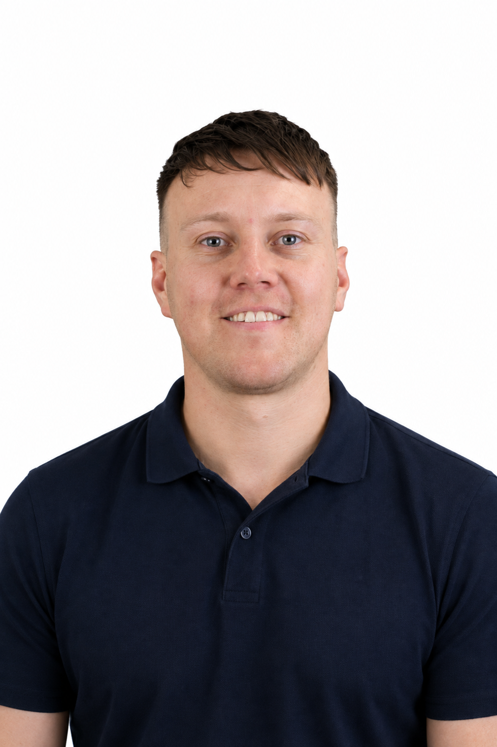 A young man with short brown hair, smiling, wearing a dark blue polo shirt, against a plain white background.
