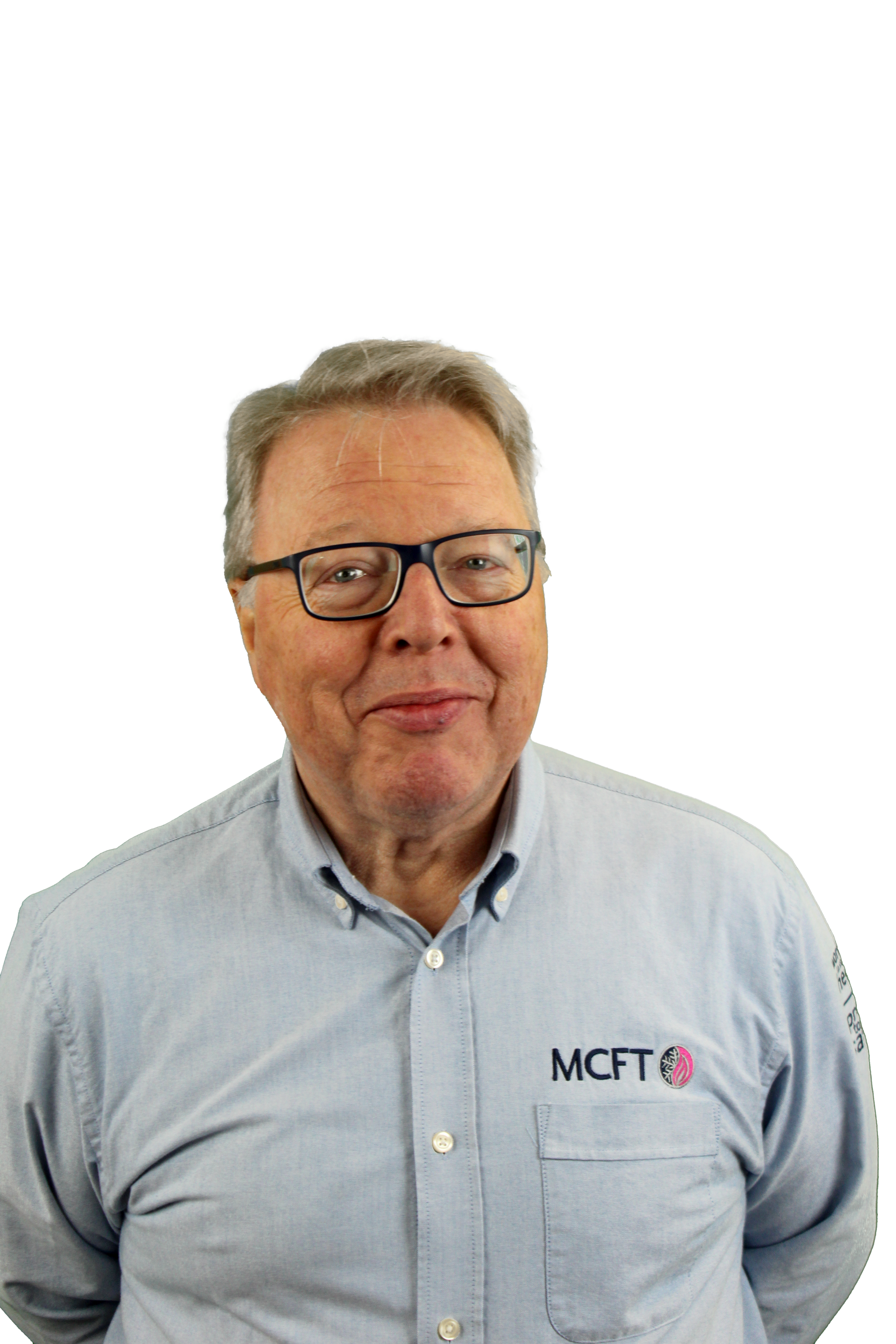 Portrait of a middle-aged man with glasses, wearing a light grey dress shirt with an embroidered logo, smiling slightly, against a white background.