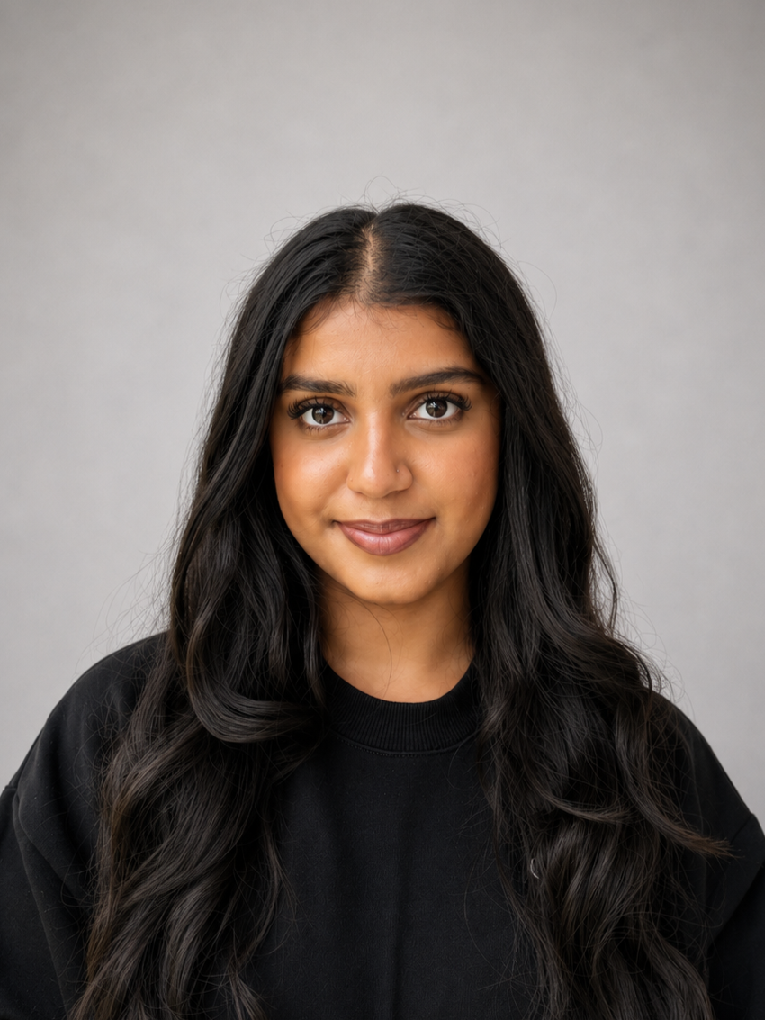 A young woman with long dark hair, brown eyes, and a subtle smile, wearing a black shirt, against a gray background.