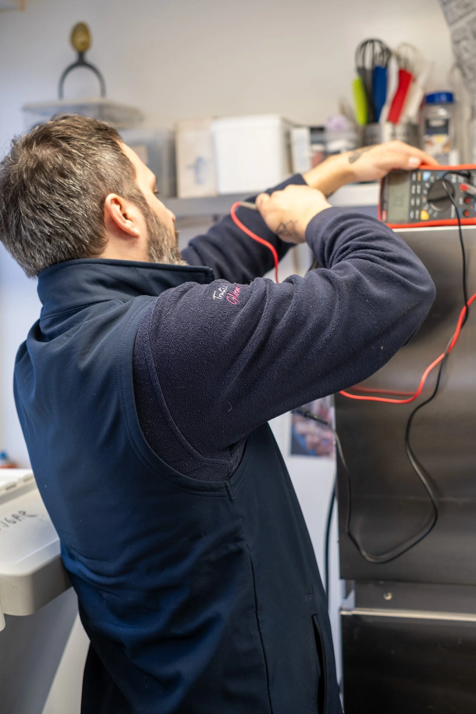 A man working with electrical testing equipment in a workshop.