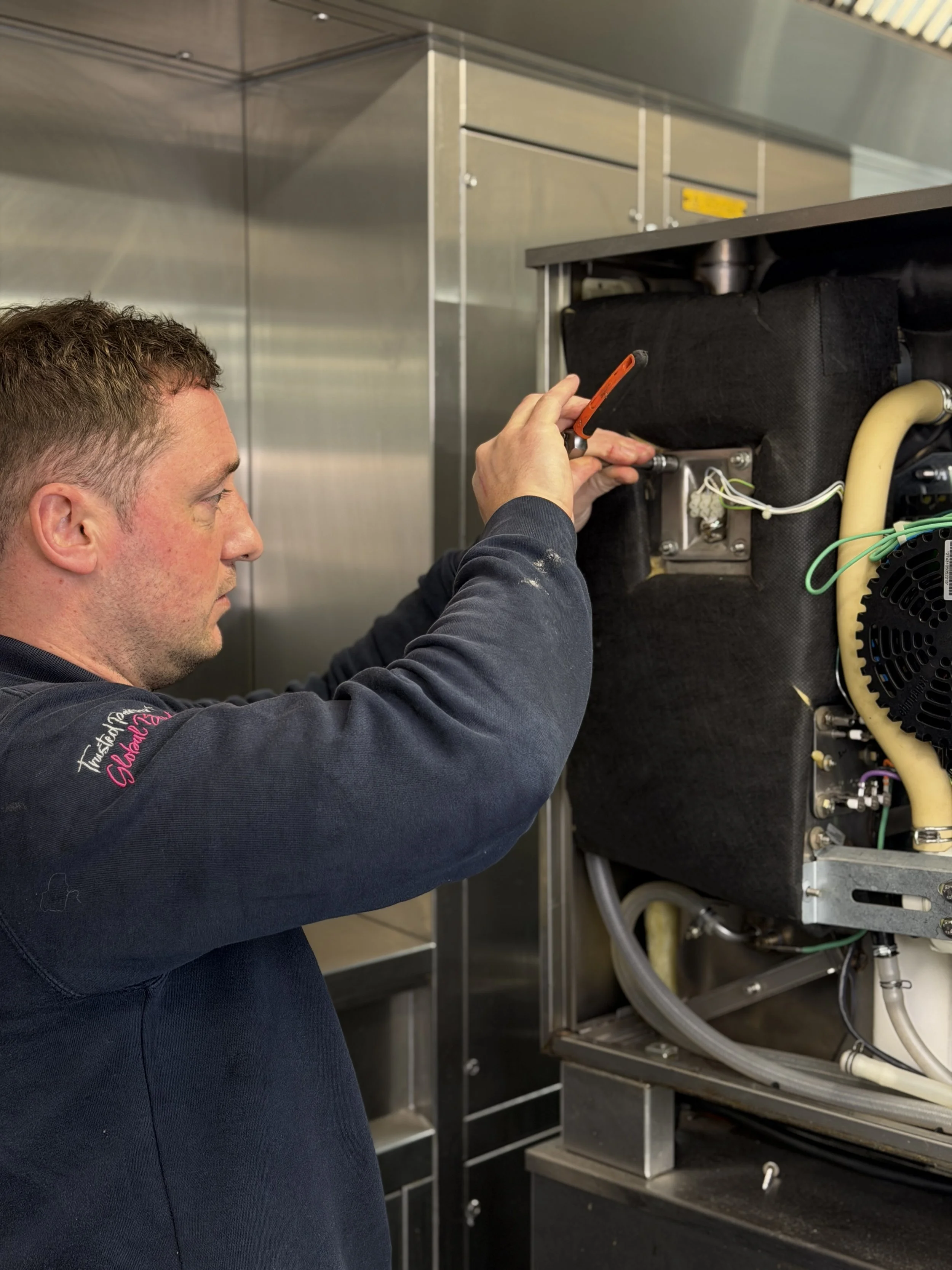 A man working on machinery in a commercial kitchen or industrial setting.
