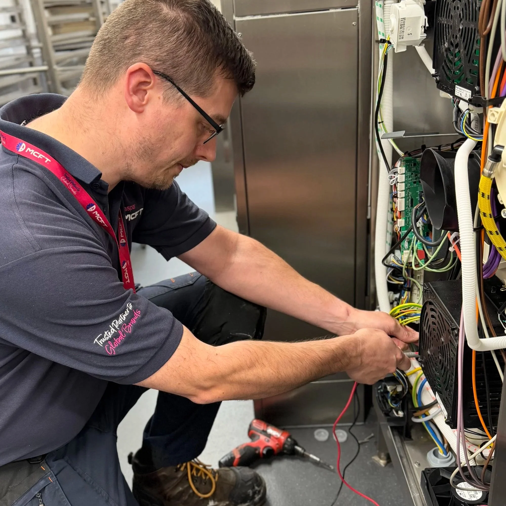 A technician working on electrical wiring inside an electrical panel or control box.