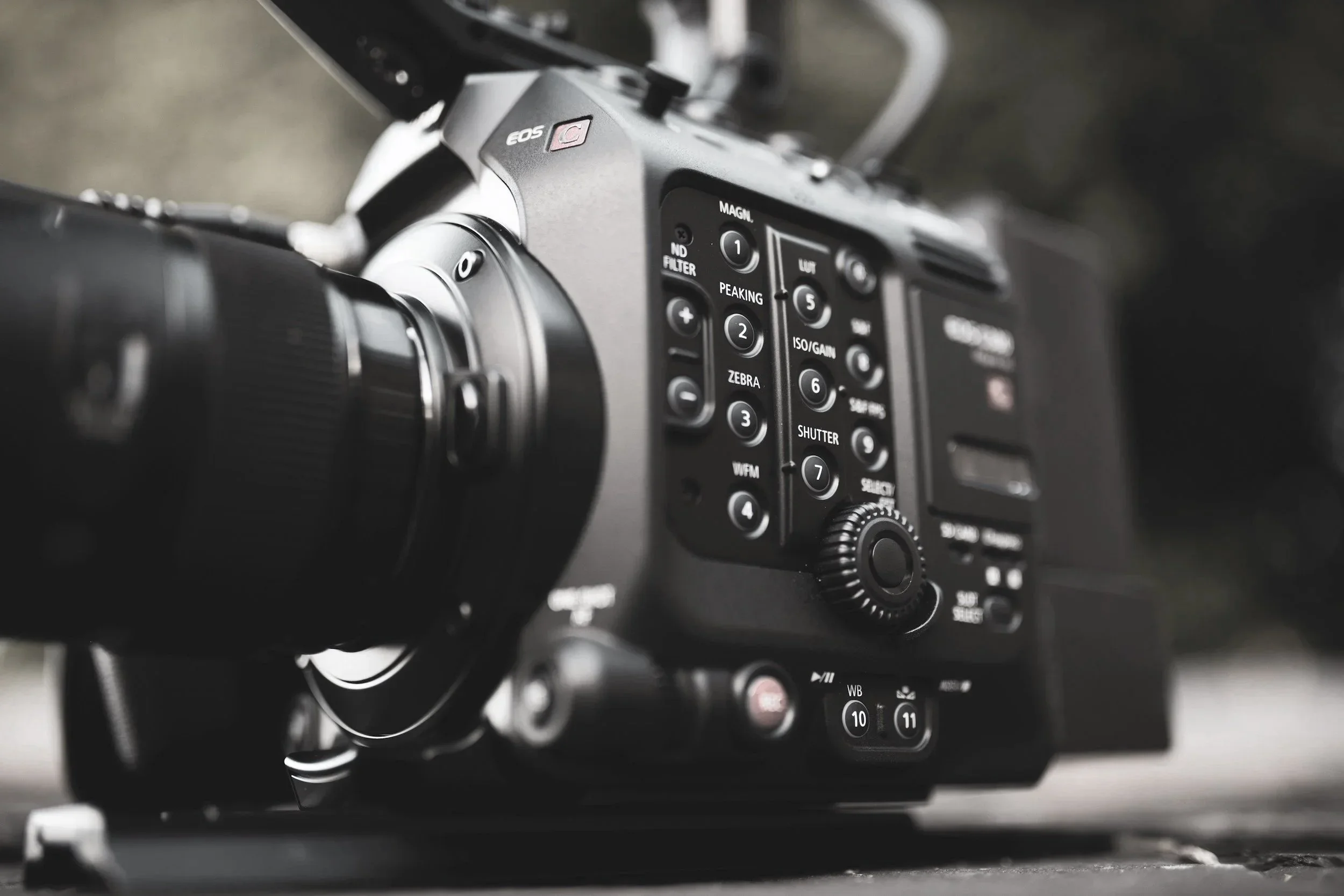 Close-up of a professional video camera showing various buttons, dials, and controls on its side.