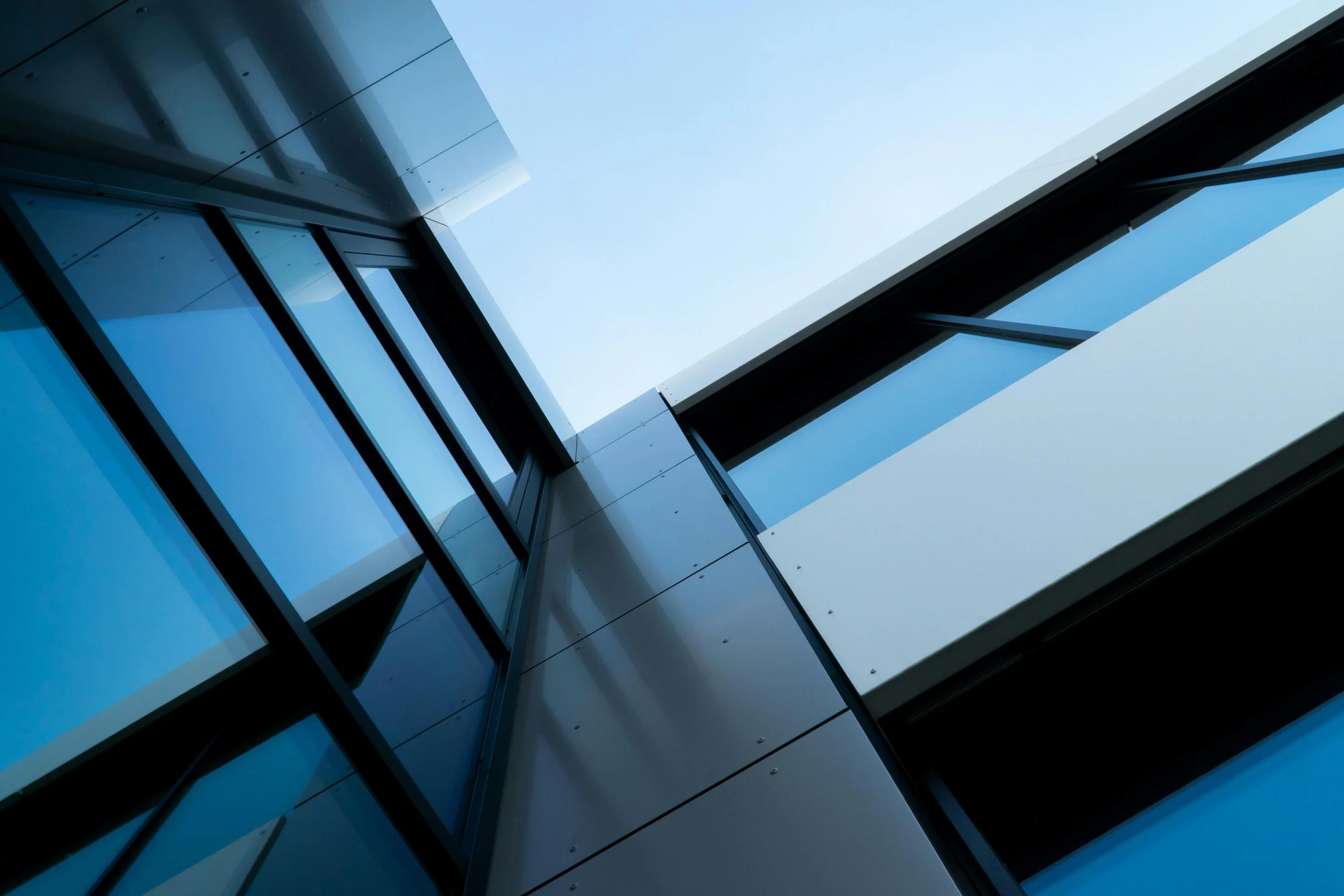 Upward view of modern building with glass windows and metal panels.