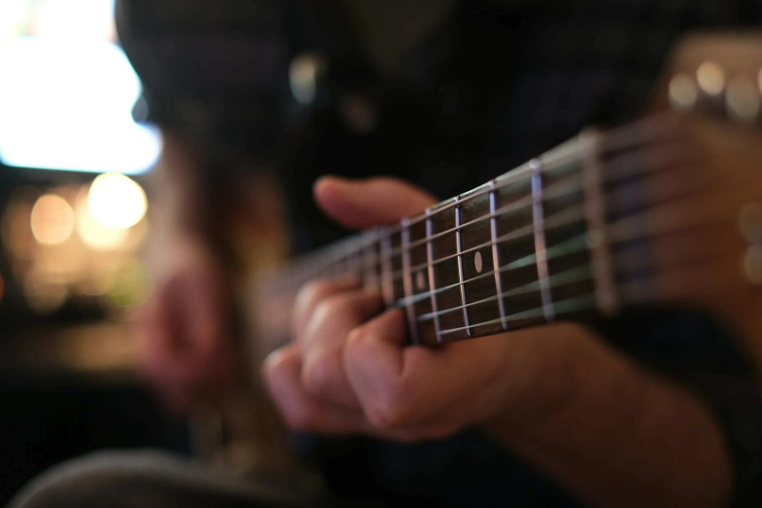 Close-up of fingers pressing strings on a guitar fretboard