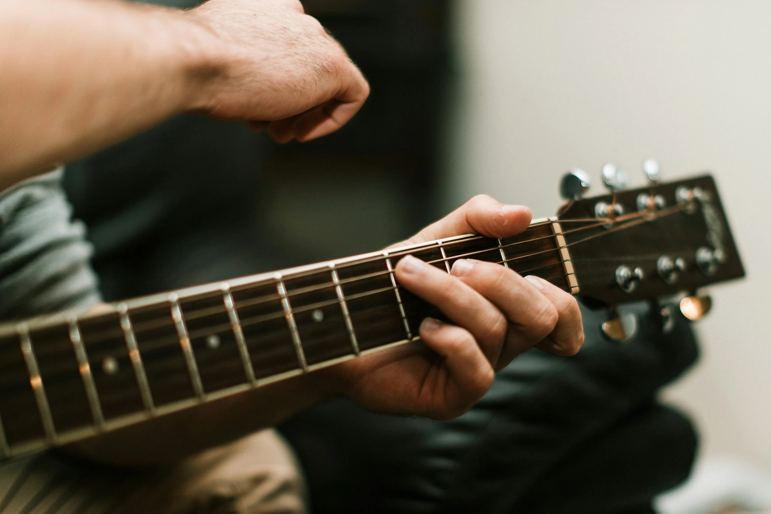 Adult guitar teacher holding acoustic guitar in Teddington, South West London