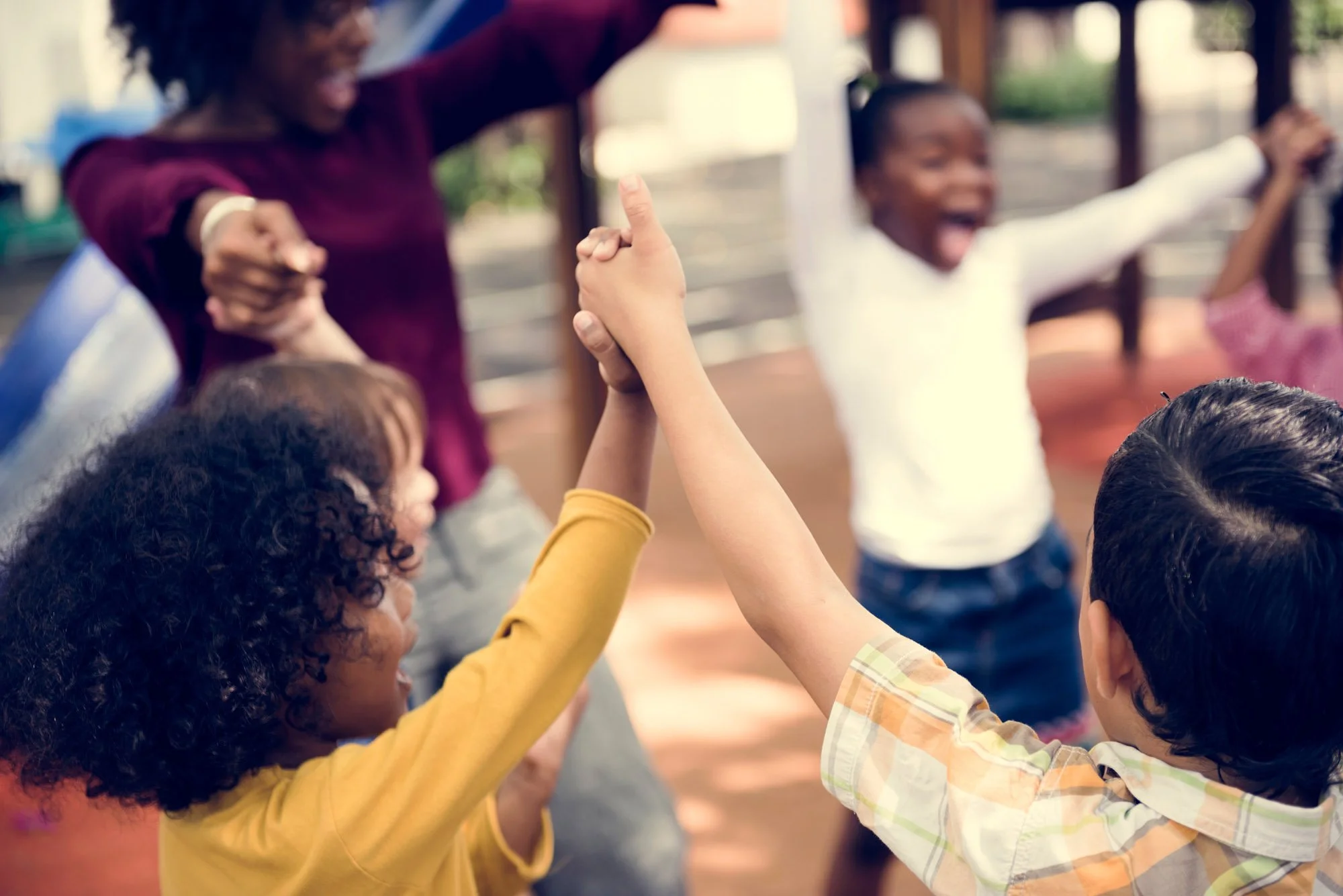 Niños que van de la mano y celebran al aire libre, sonriendo y disfrutando de la compañía de los demás.