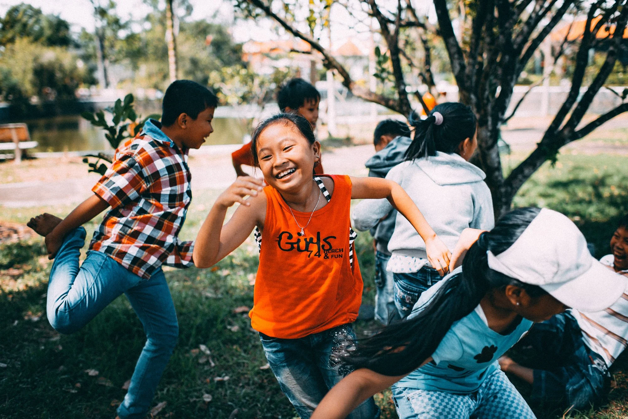 Un grupo de niños jugando al pilla-pilla o a algún juego en grupo al aire libre en un parque durante el otoño, con algunos niños corriendo y sonriendo.