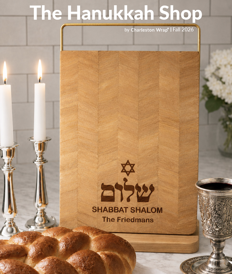 A wooden Shabbat menu or table setting with candles, challah bread, a silver Kiddush cup, and a sign reading 'Shabbat Shalom' by the Friedmans.