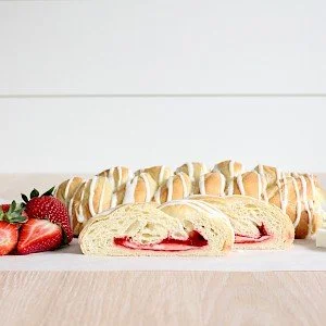 Strawberry and cream-filled sandwich and a long strawberry-filled baguette on a white surface.