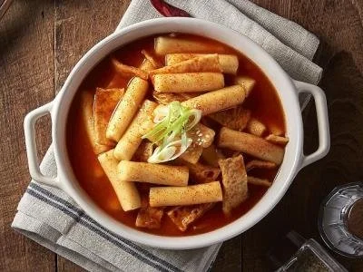 A bowl of Korean spicy stew with rice cakes and green onions