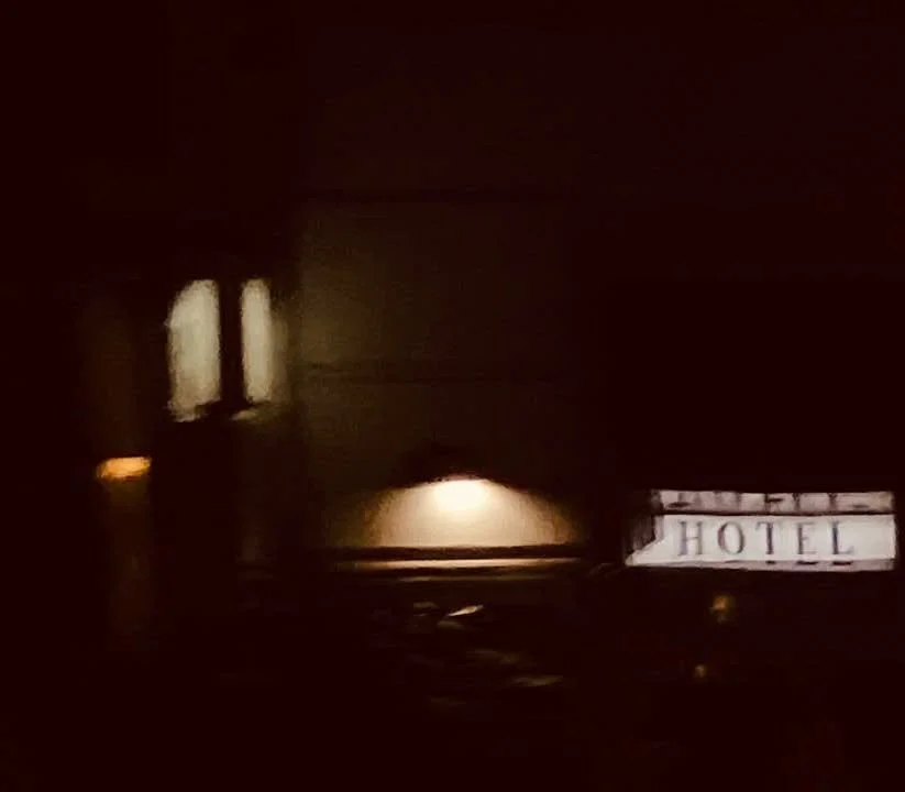 Der Eingang eines Hotels bei Nacht, schwach beleuchtet.