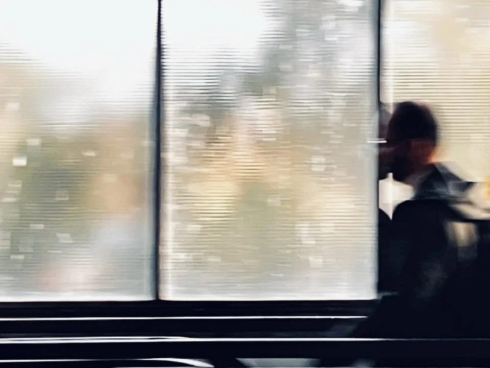 Kurz vor Sonnenuntergang ein Mann sitzt an einem Fenster und schaut nach draußen, während die Sonne durch die Fensterläden scheint.