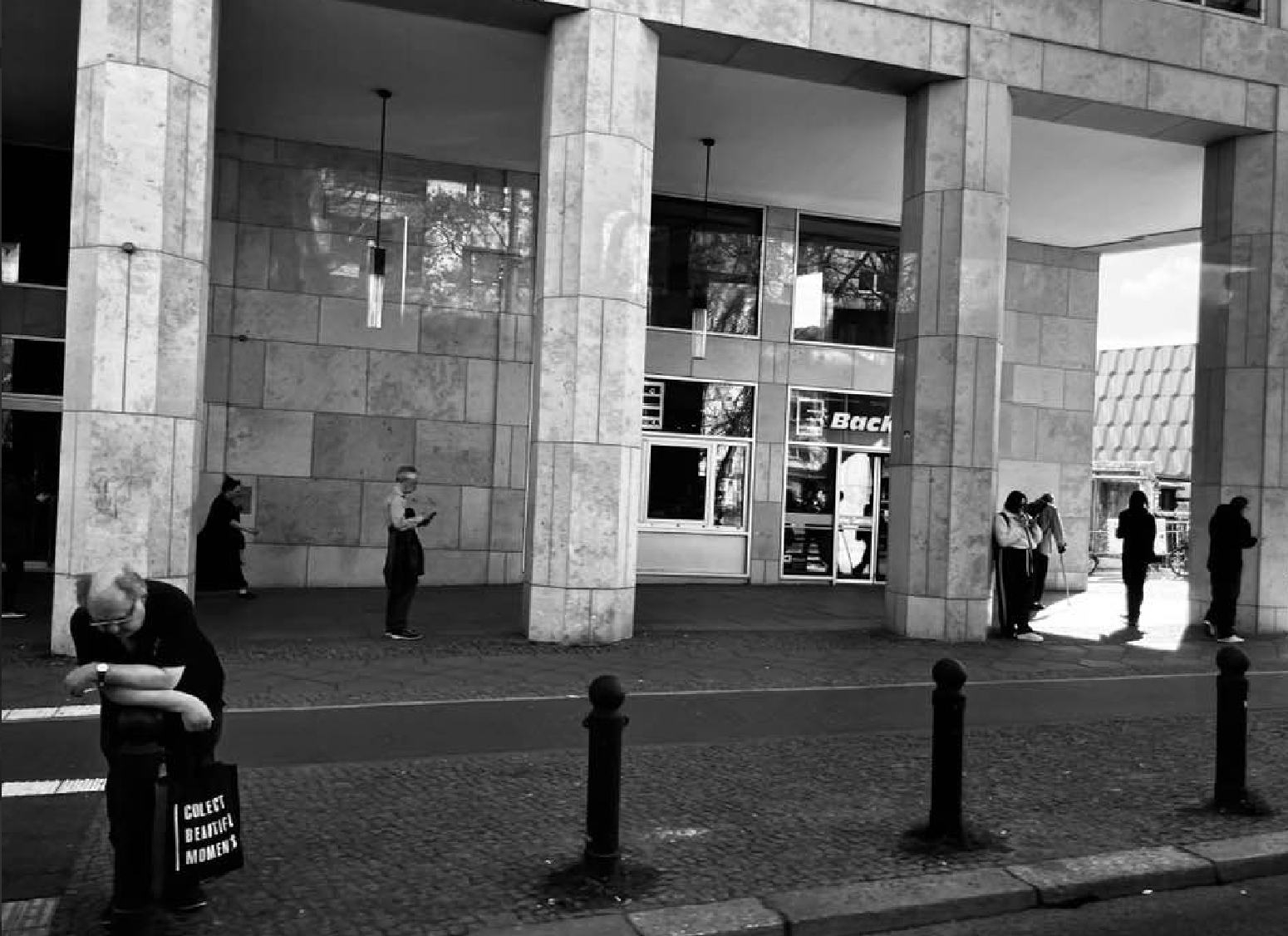 Personen m öffentlichen Raum, mehrere Stories in einem Bild. Eine Person (die Hauptperson), überfordert mit der Hitze und City Vibes, trägt eine Tasche auf der "Collect Beautiful Moments" steht. Das gab dem Bild auch den Titel