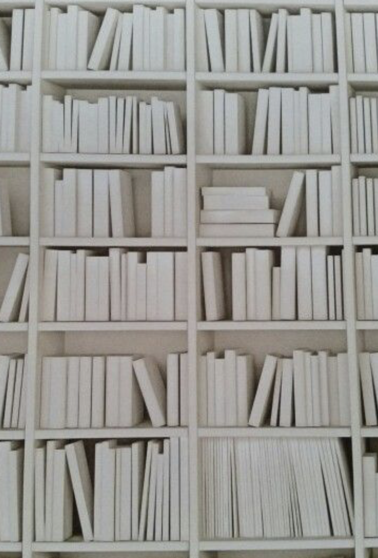 White bookshelf filled with many white books arranged in various orientations.