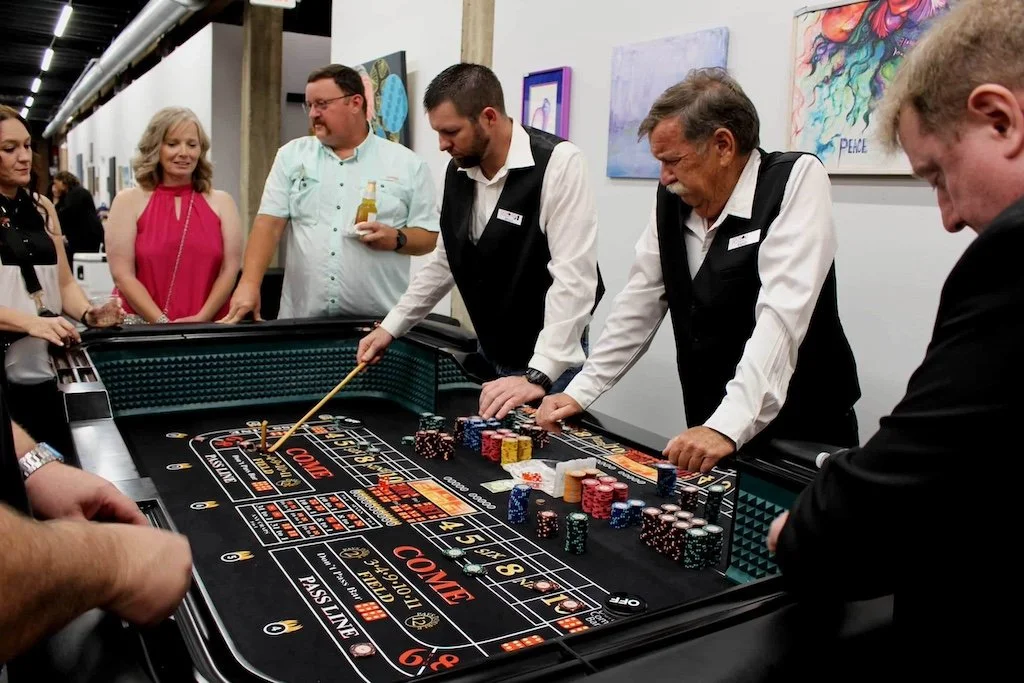 People gather around a busy craps table at a casino, with two dealers overseeing the game and players watching closely.