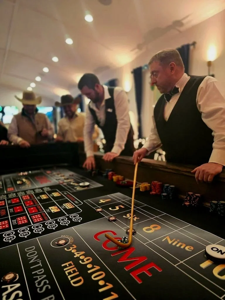 People playing roulette at a casino table inside a nicely lit room.