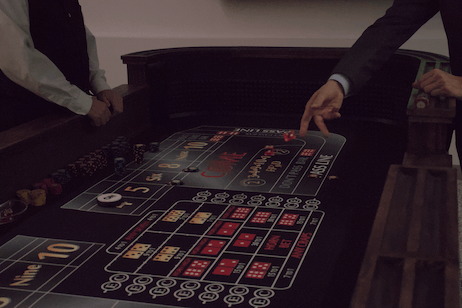 A person's hand over a craps table shooting a pair of dice