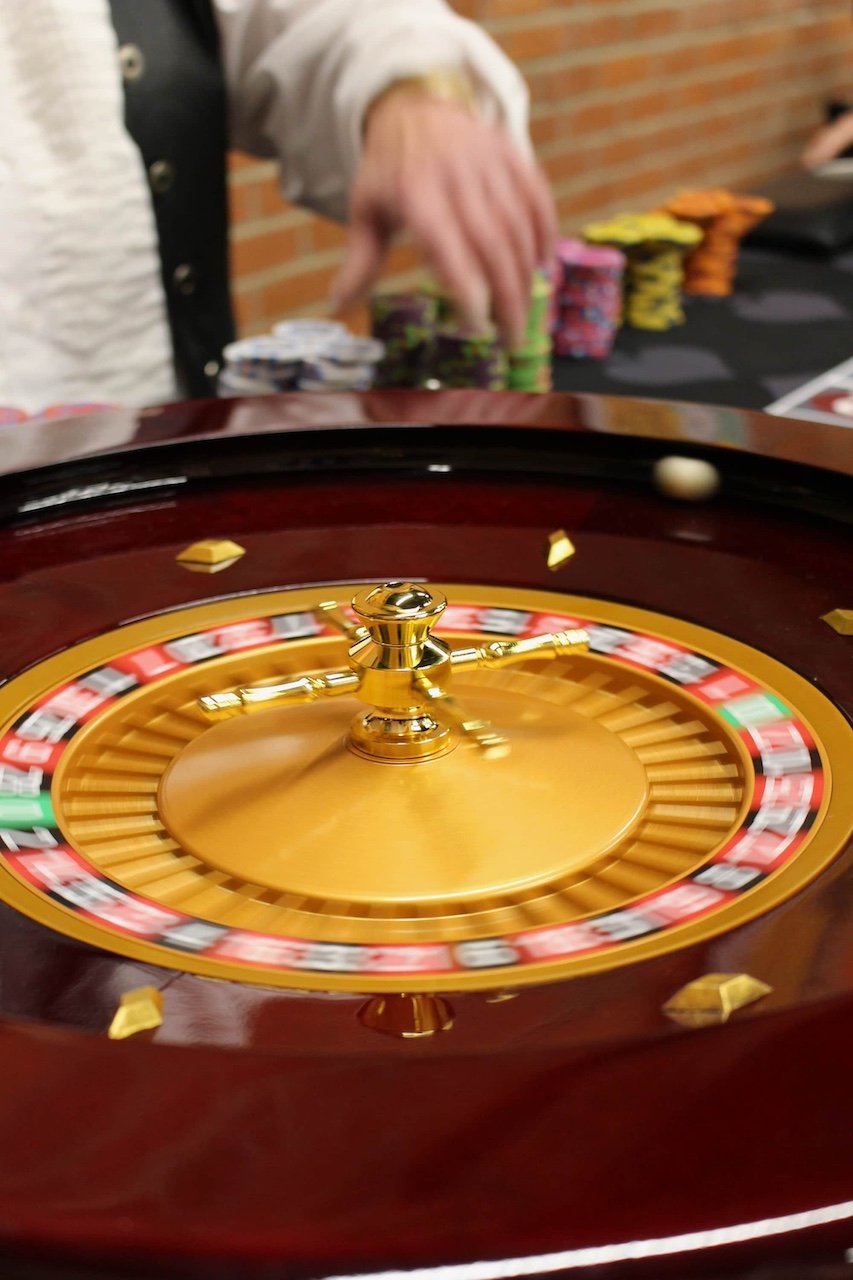 A spinning roulette wheel at Royale 54, with a hand reaching for poker chips on the table in the background.