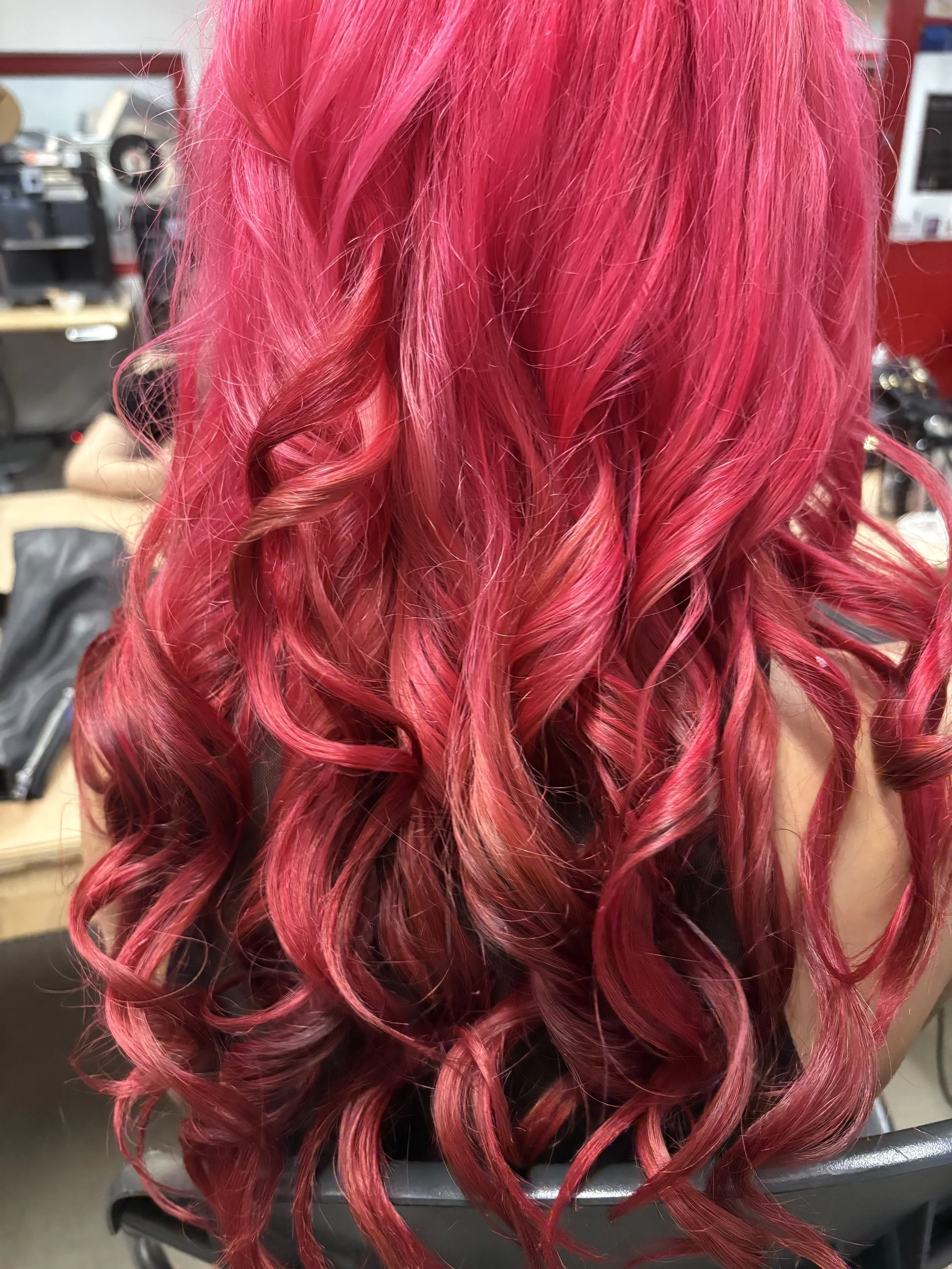 Close-up of long, curly, bright pink hair with some reddish highlights.