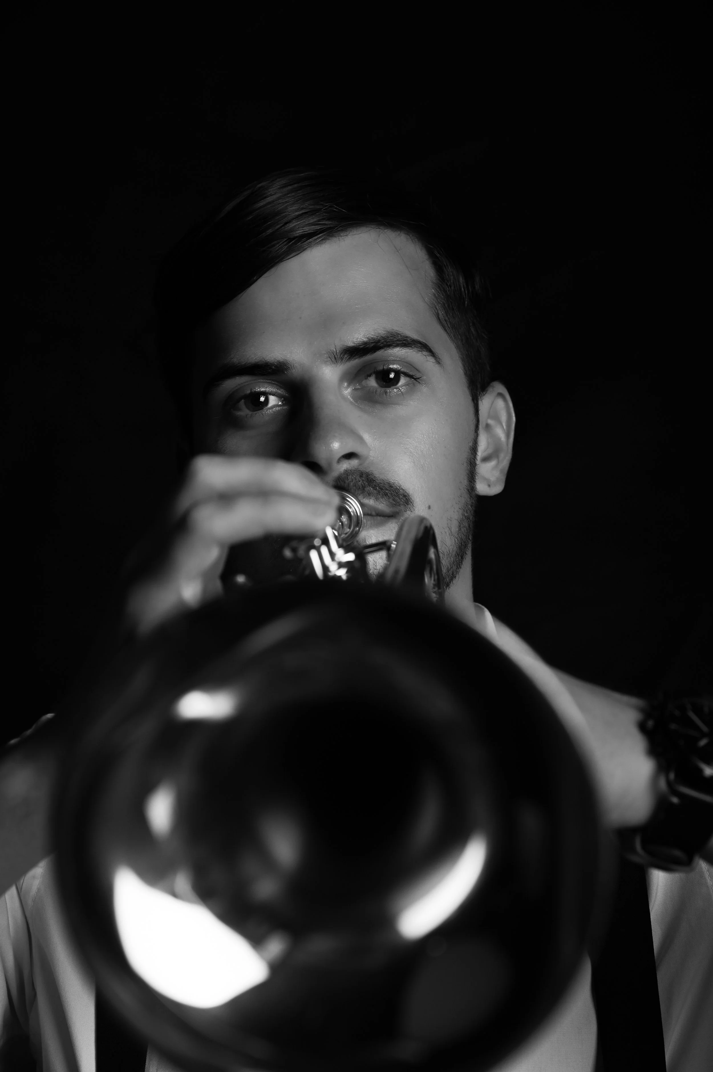 Schwarz-weiß-Foto eines Mannes, der in eine Kamera oder ein Instrument schaut, das nah am Objektiv ist. Der Fokus liegt auf den Augen und dem Gesicht des Mannes, während das Objektiv im Vordergrund unscharf ist.