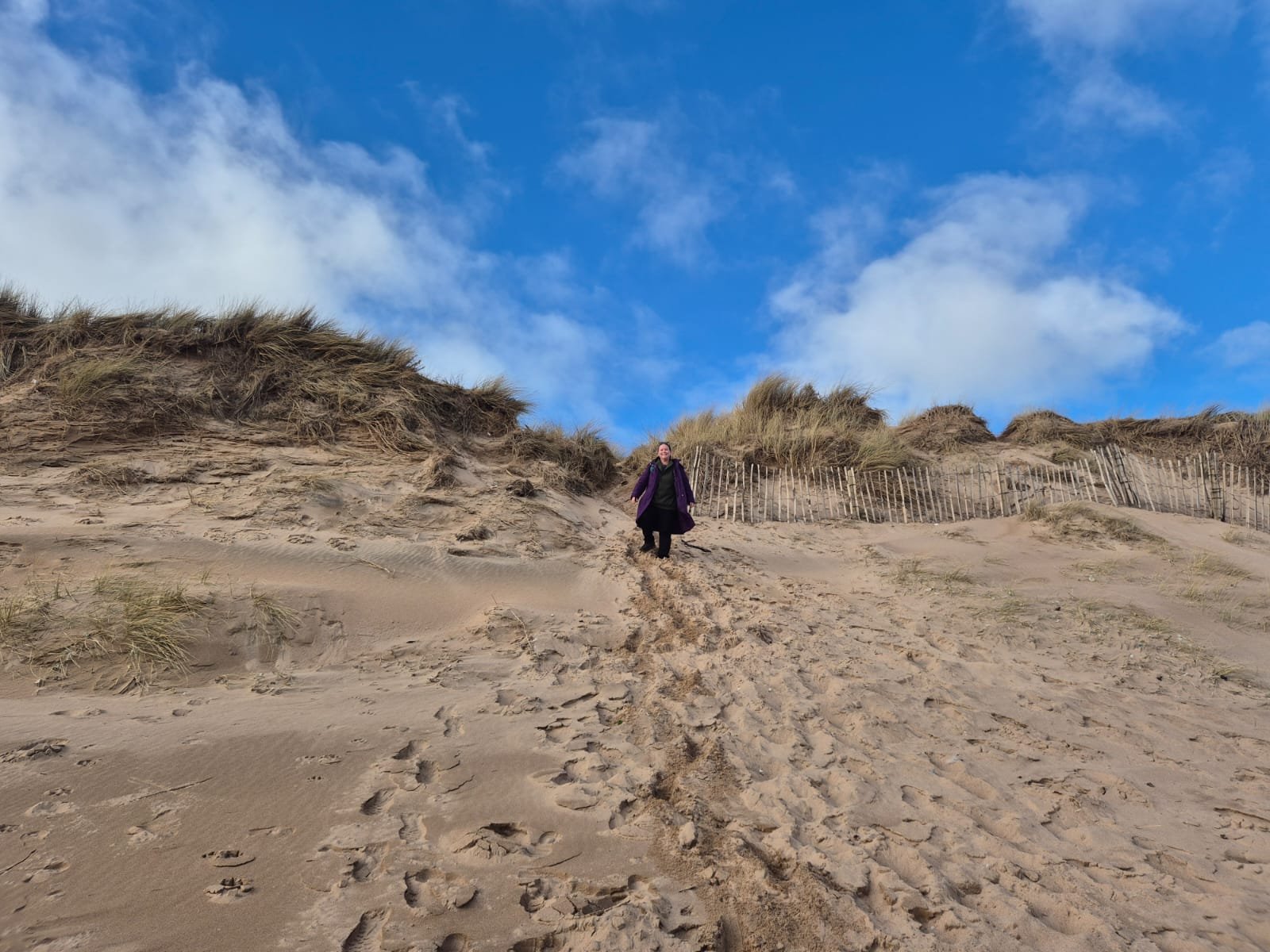 Picture of a woman walking down a steep sand dune
