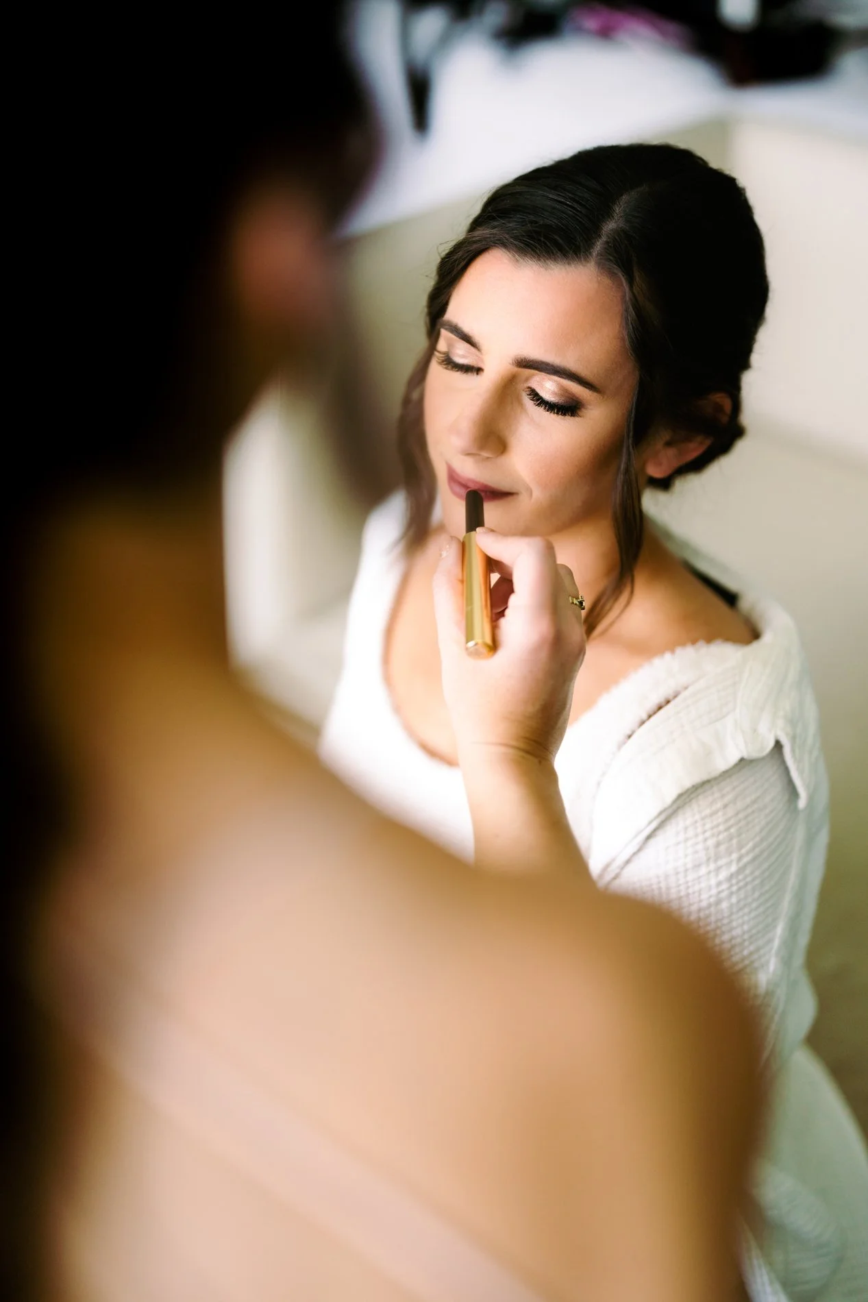 Bride getting makeup applied by bridal makeup artist.