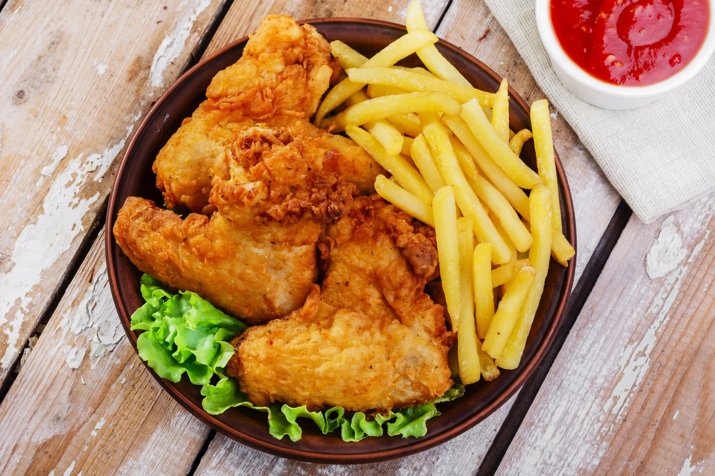 Fried chicken with French fries, lettuce, and a side of ketchup