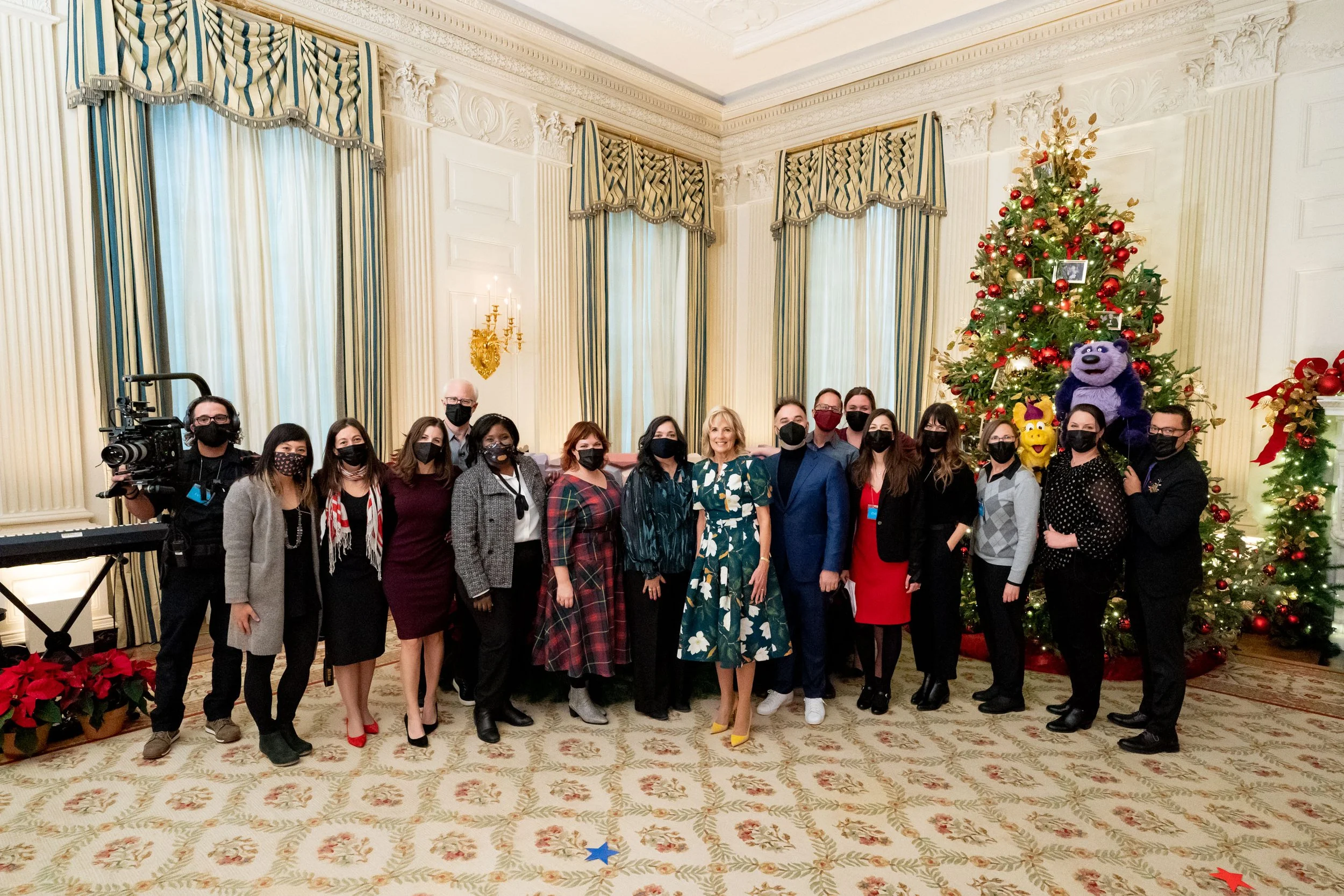 PBS KIDS staff at the White House with First Lady of the United States Jill Biden wearing masks standing together in front of a decorated Christmas tree.