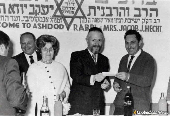 The Hechts at an official welcome in Ashdod, Israel. Rabbi Hecht is handing a check of funds collected in the U.S. to one of the heads of the city. 