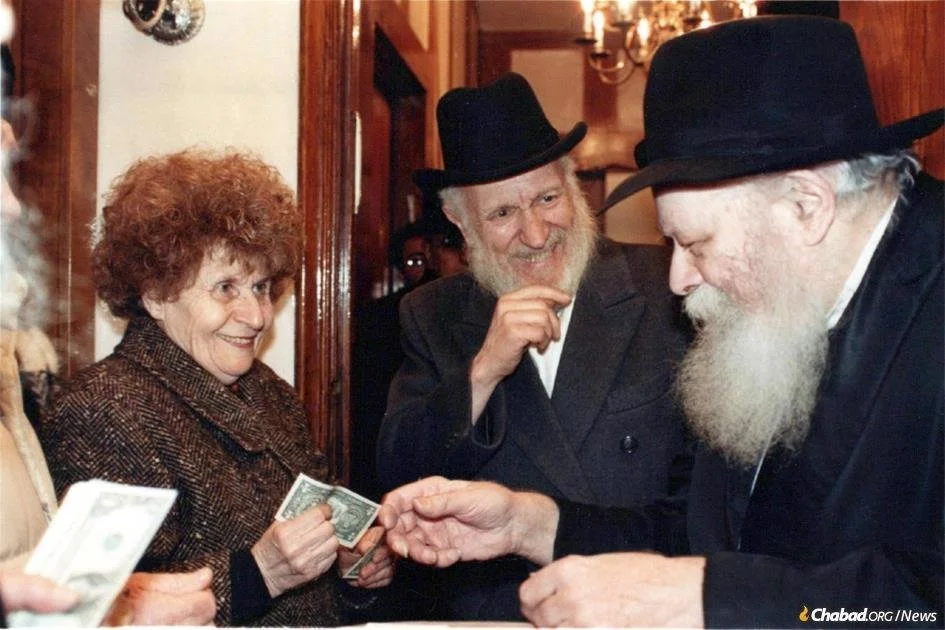 Rebbetzin Chave Hecht and Rabbi J.J. Hecht receive a dollar and a blessing from the Rebbe before a trip to South Africa in 1989.