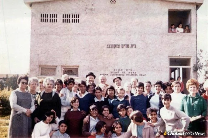 Rabbi and Rebbetzin Hecht with a group of children in front of the Miriam Zuckerberg Children's Home in the Colony of Hope that they founded.