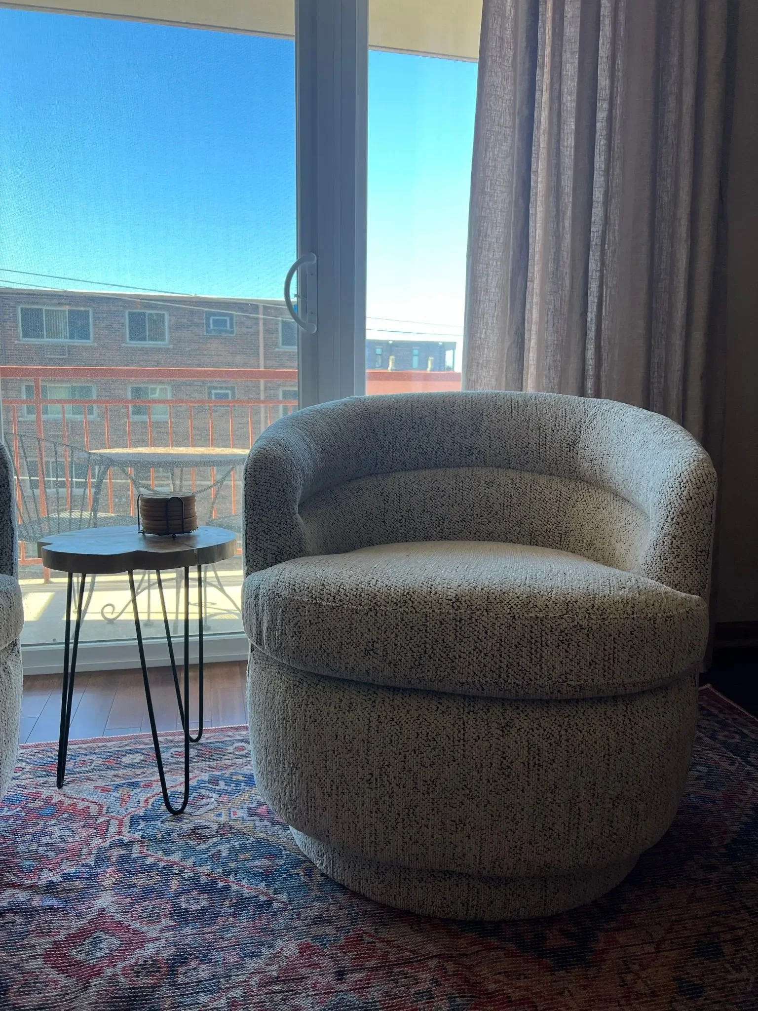 View of the window behind the seating chair and wood side table 